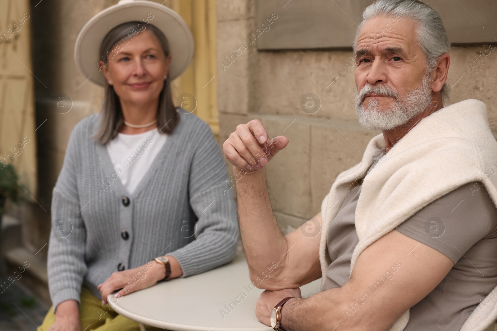 Photo of Affectionate senior couple sitting in outdoor cafe