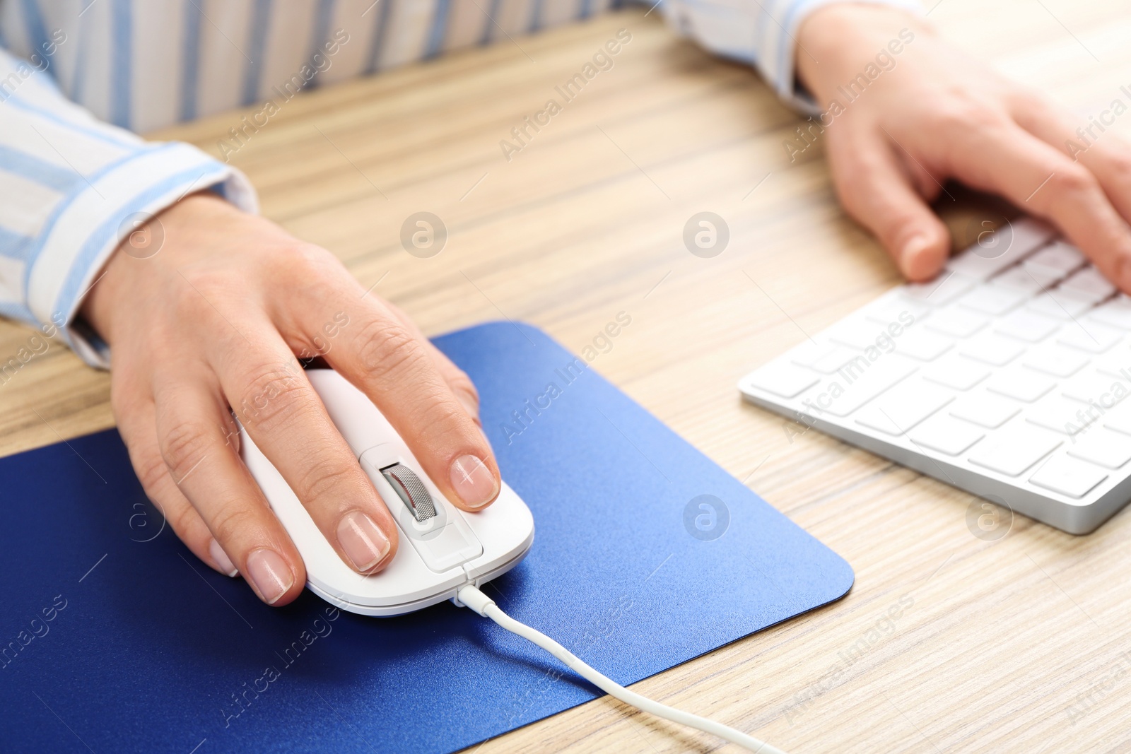 Photo of Woman using modern wired optical mouse at office table, closeup