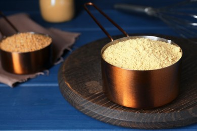 Photo of Saucepan with mustard powder on blue wooden table. Space for text