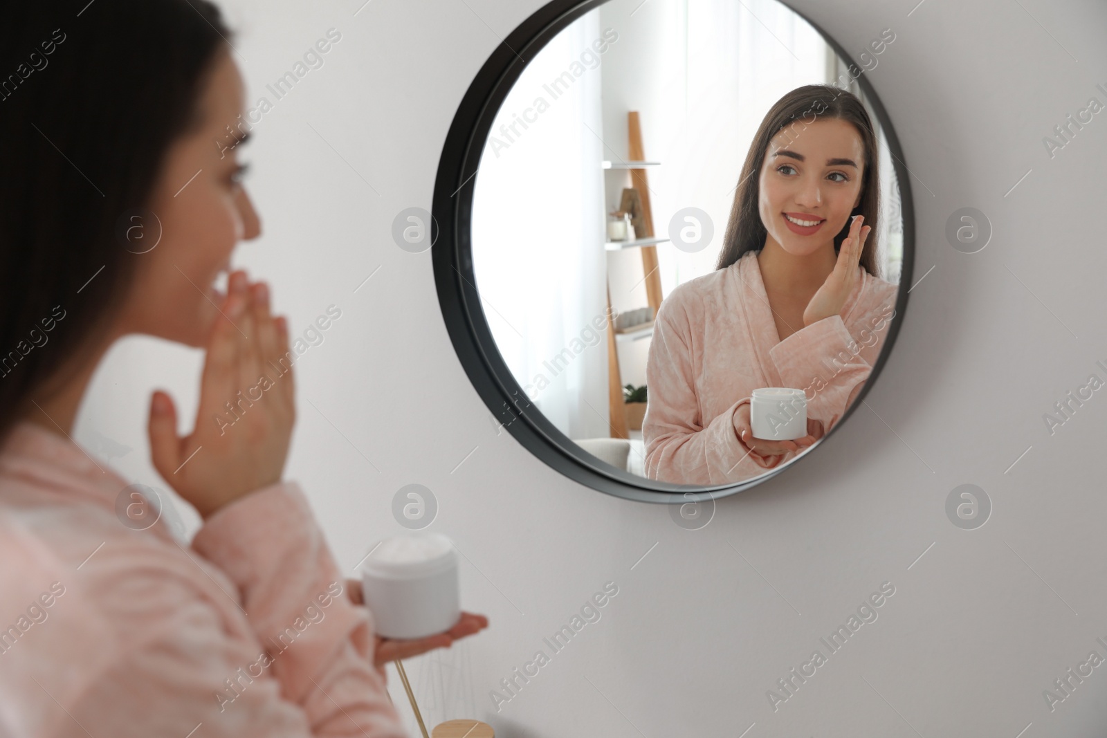 Photo of Young woman applying face cream at home. Morning routine