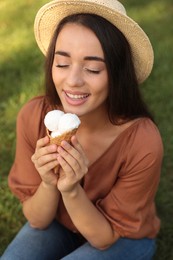 Happy young woman with delicious ice cream in waffle cone outdoors