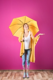 Woman with yellow umbrella near color wall