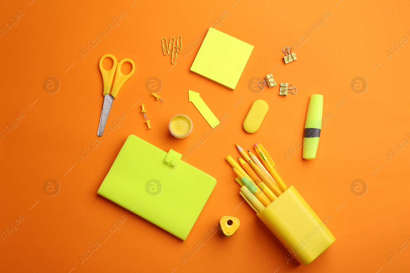 Photo of Different bright school stationery on orange background, flat lay