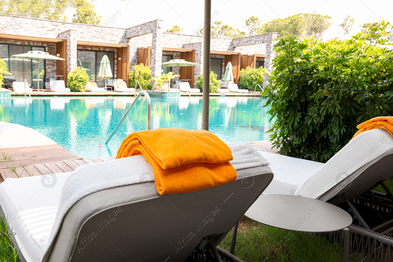 Photo of Sunbeds near outdoor swimming pool at luxury resort