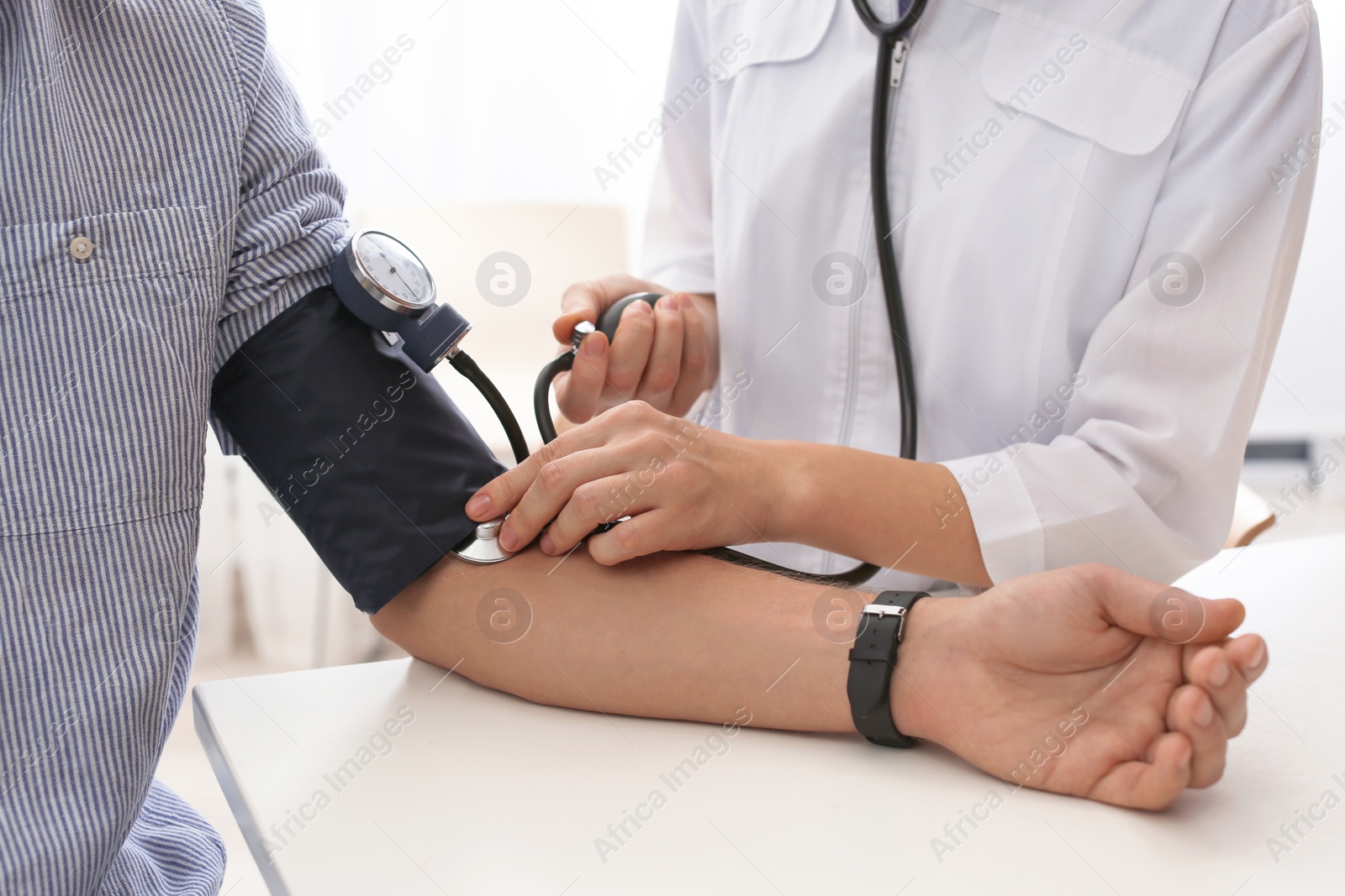 Photo of Doctor checking patient's blood pressure in hospital, closeup. Cardiology concept