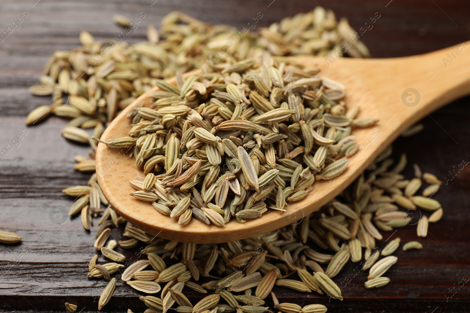 Photo of Spoon with fennel seeds on wooden table, closeup