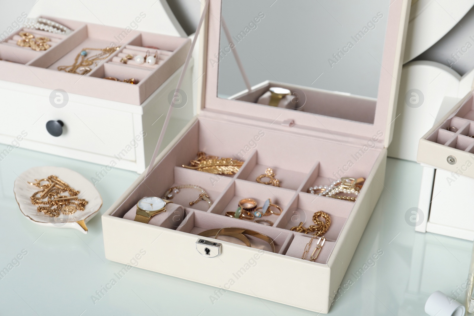 Photo of Elegant jewelry boxes with beautiful bijouterie and wristwatch on dressing table