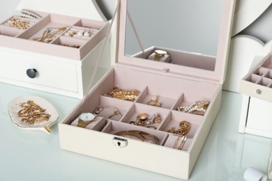 Photo of Elegant jewelry boxes with beautiful bijouterie and wristwatch on dressing table