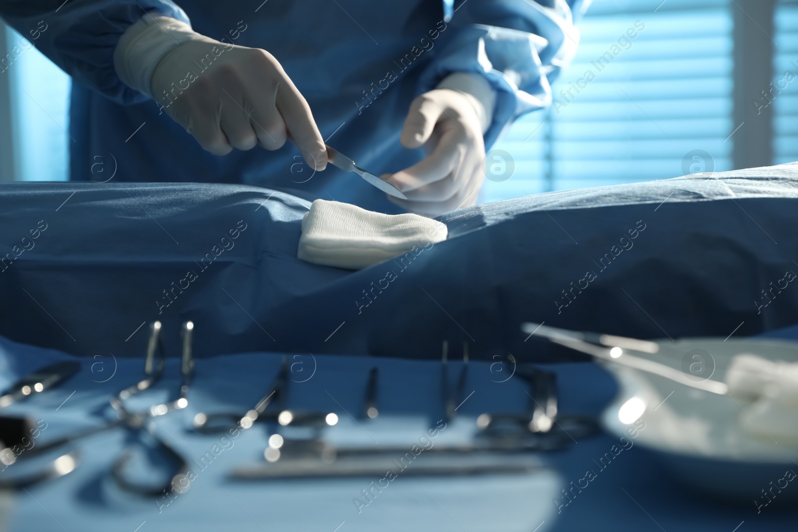 Photo of Professional surgeon with instruments performing operation in clinic, closeup