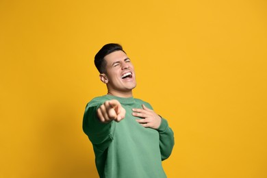 Photo of Handsome man laughing on yellow background. Funny joke