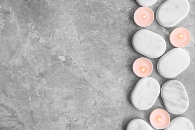 Flat lay composition with spa stones and candles on grey marble background. Space for text