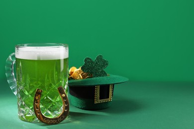 Photo of St. Patrick's day party. Green beer, leprechaun hat with gold, horseshoe and decorative clover leaf on green background. Space for text