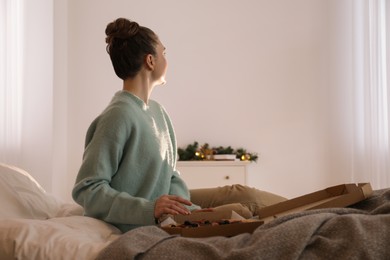 Woman with pizza watching movie via video projector at home