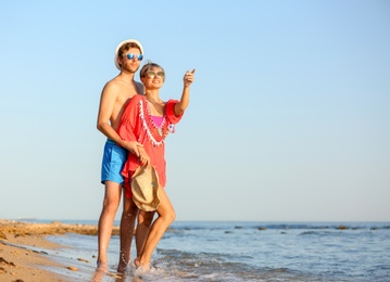 Happy young couple near water on beach. Space for text