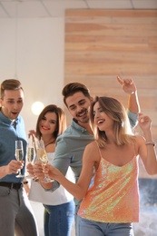 Happy friends with champagne in glasses having party indoors