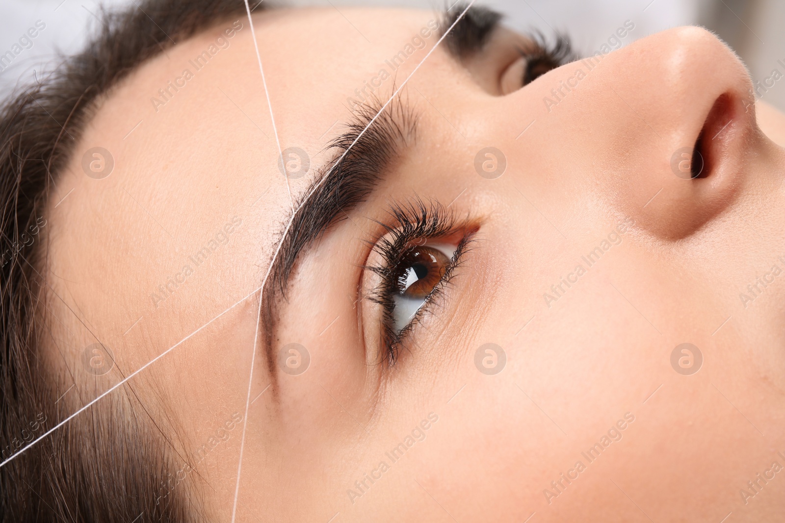 Photo of Young woman having professional eyebrow correction procedure, closeup