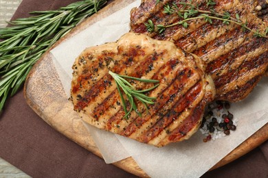 Photo of Delicious grilled pork steaks with herbs and spices on table, top view