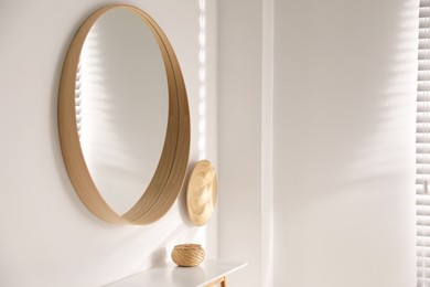Stylish round mirror hanging on white wall in room