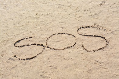 Photo of SOS message written on sandy beach outdoors