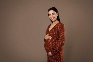 Happy pregnant woman near dark wall, space for text. Baby shower party