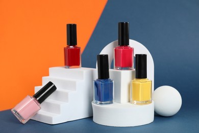 Photo of Stylish presentation of bright nail polishes in bottles on color background