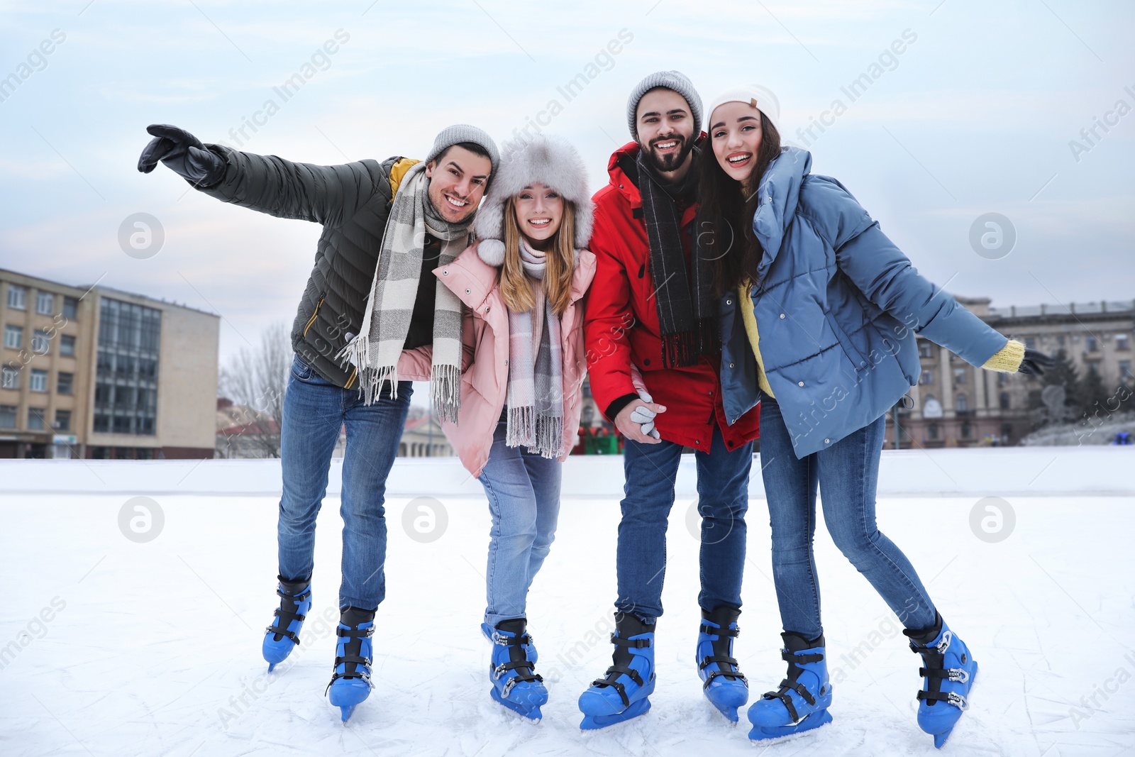 Image of Happy friends at ice skating rink outdoors