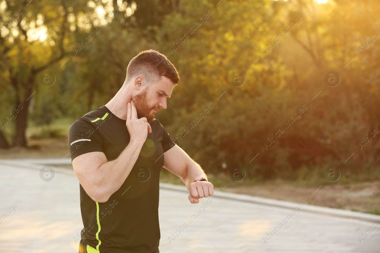 Photo of Young man checking pulse after workout in park