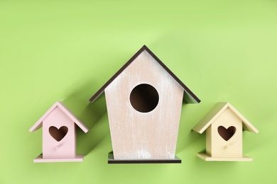 Photo of Collection of handmade bird houses on green background, flat lay