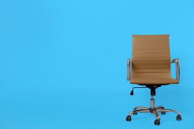 Comfortable office chair on light blue background, space for text