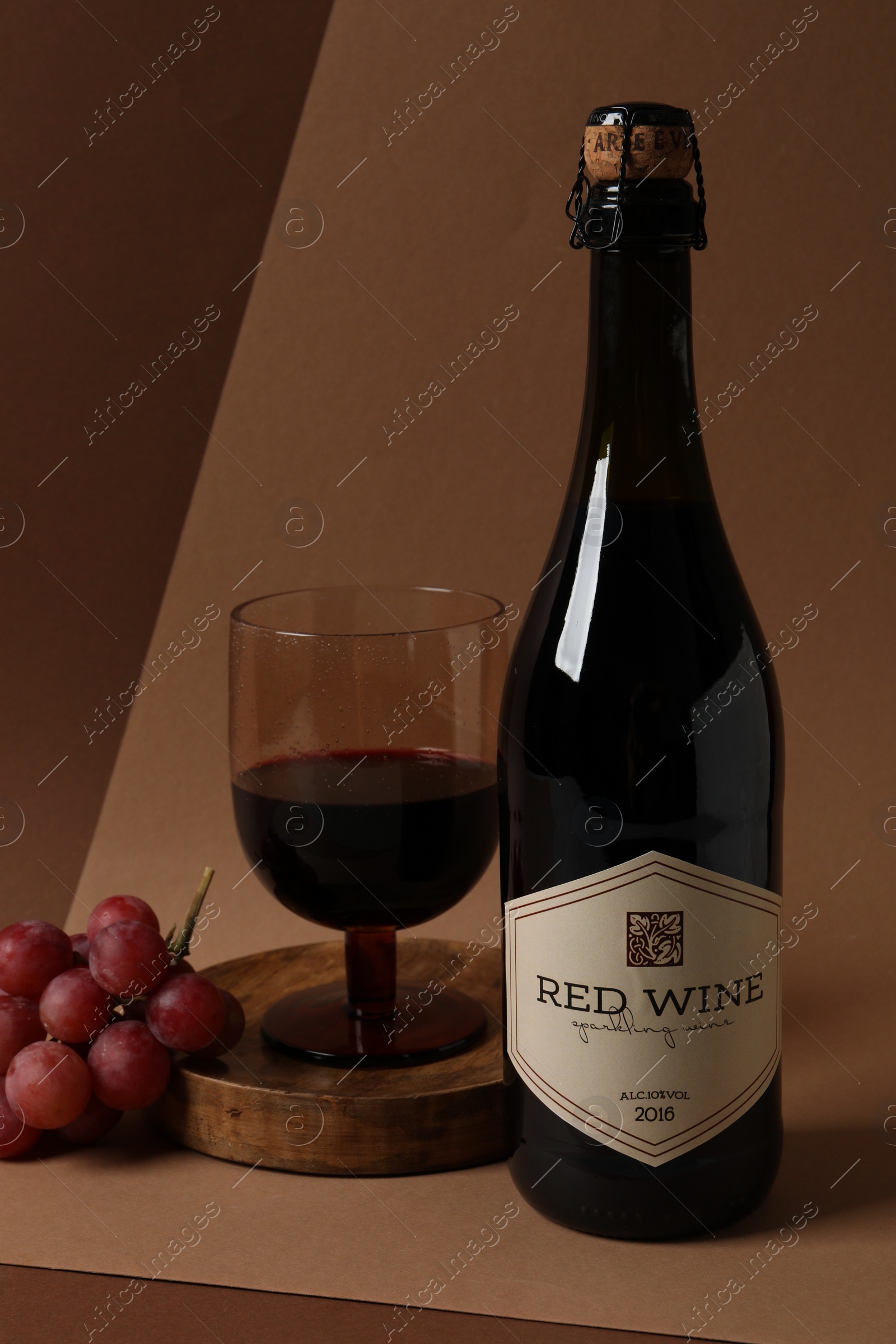 Photo of Delicious red wine and grapes on brown background