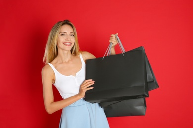Happy young woman with shopping bags on red background. Black Friday Sale