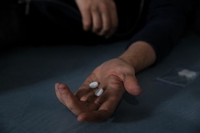 Photo of Young addicted man holding drugs, closeup view