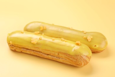 Photo of Delicious eclairs covered with glaze on yellow background