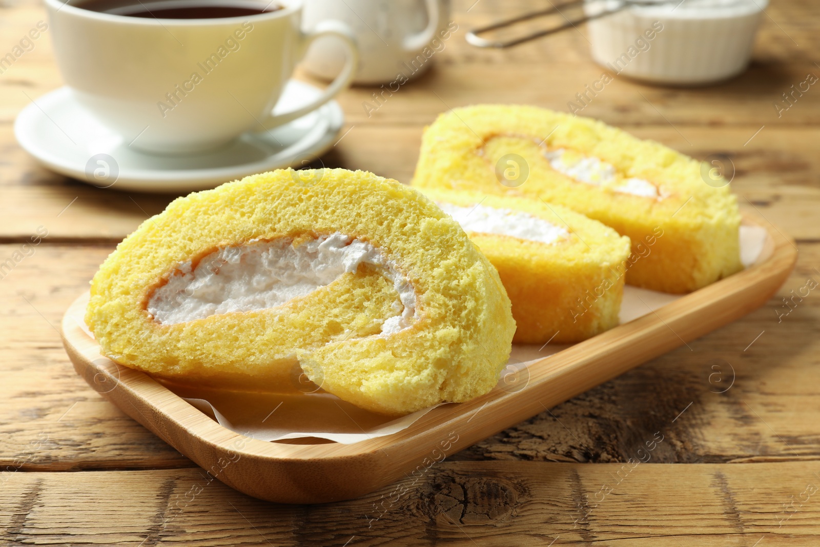 Photo of Delicious cake roll with cream filling on wooden table, closeup