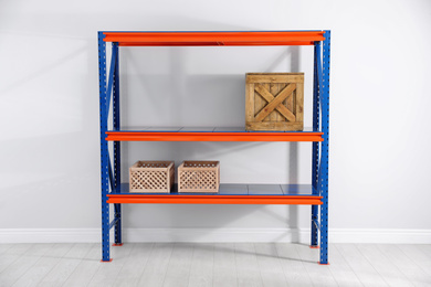 Photo of Metal shelving unit with wooden crates near light wall indoors