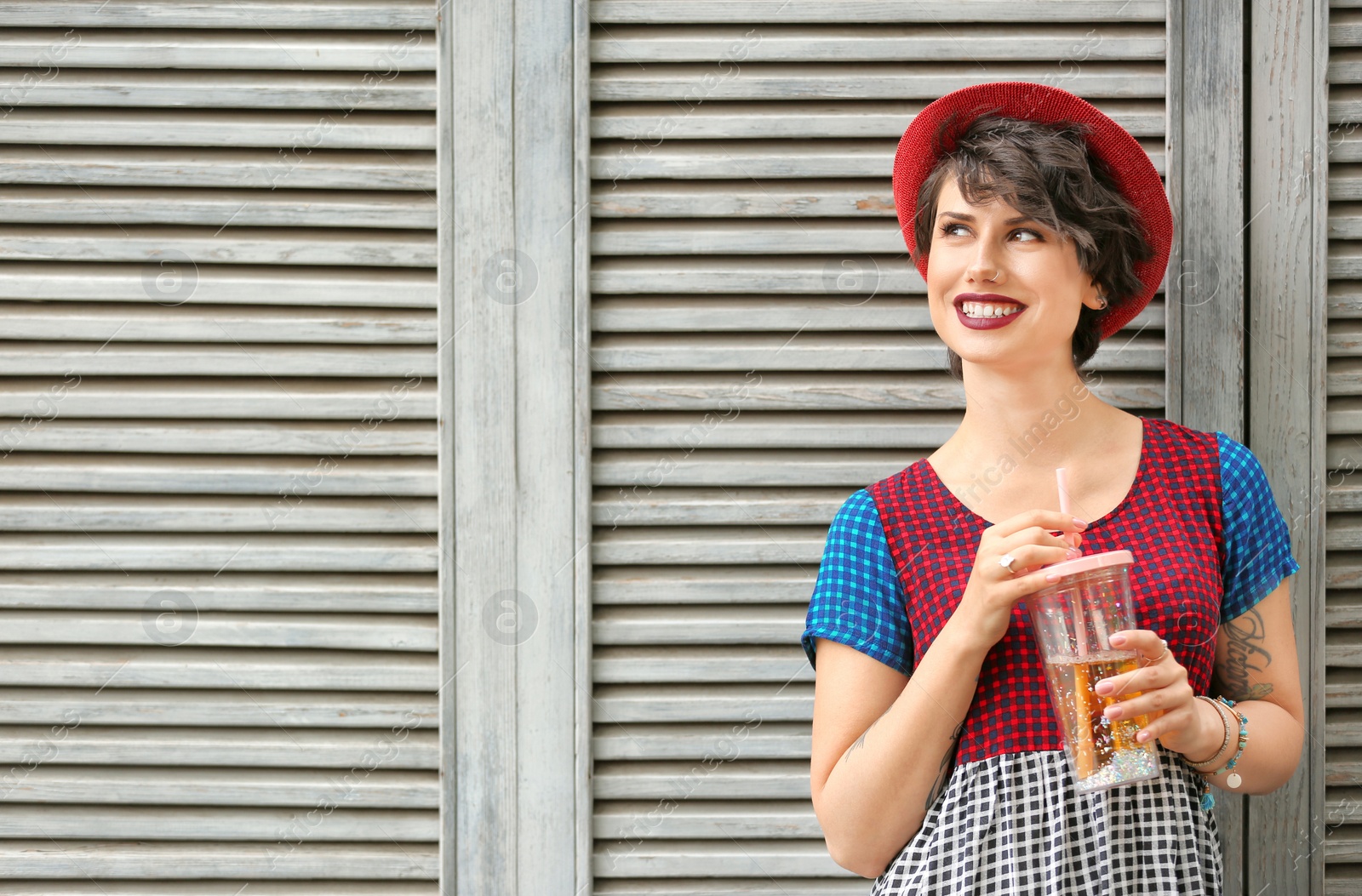 Photo of Young woman with cup of tasty lemonade near wooden wall