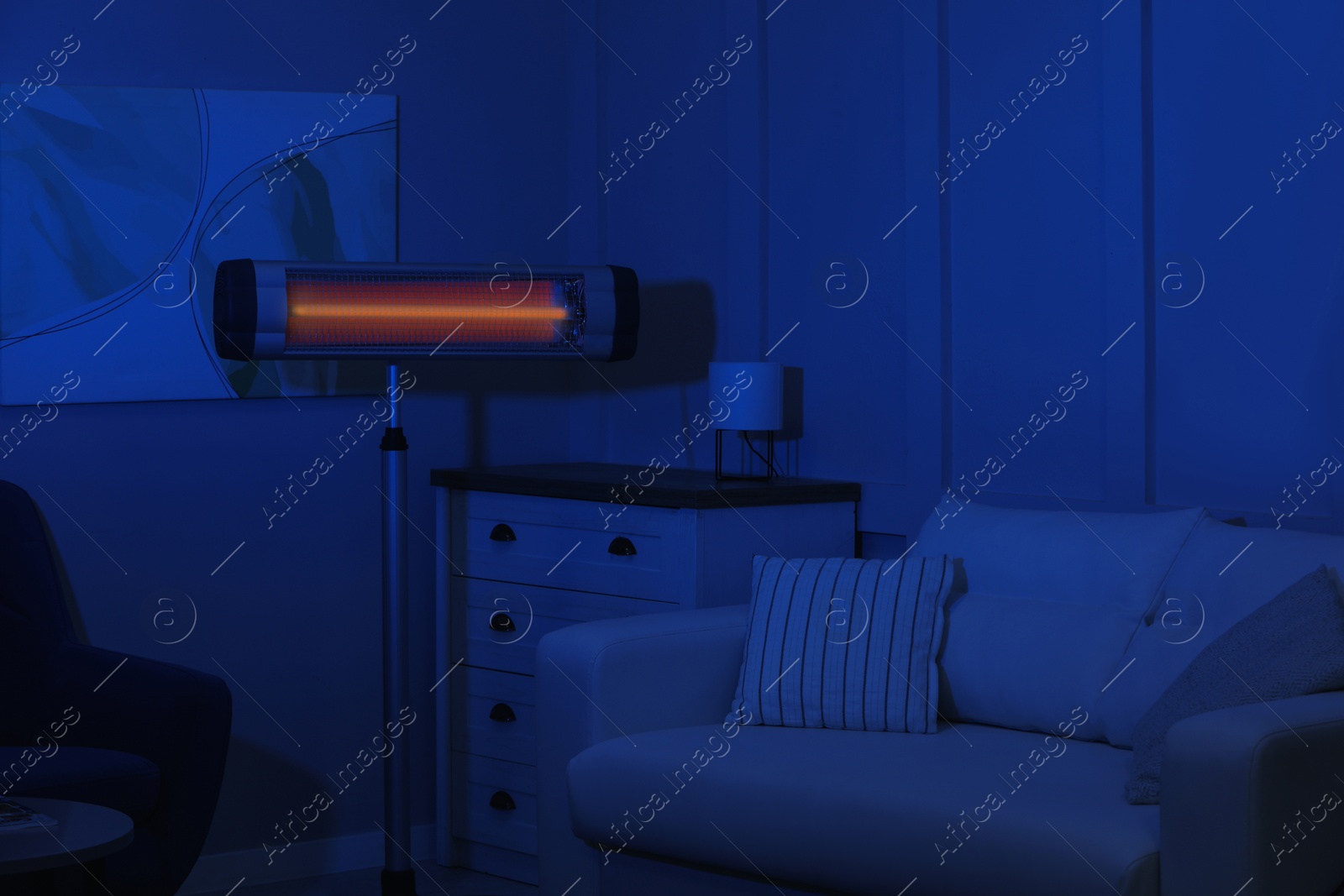 Photo of Electric infrared heater in dark living room at night