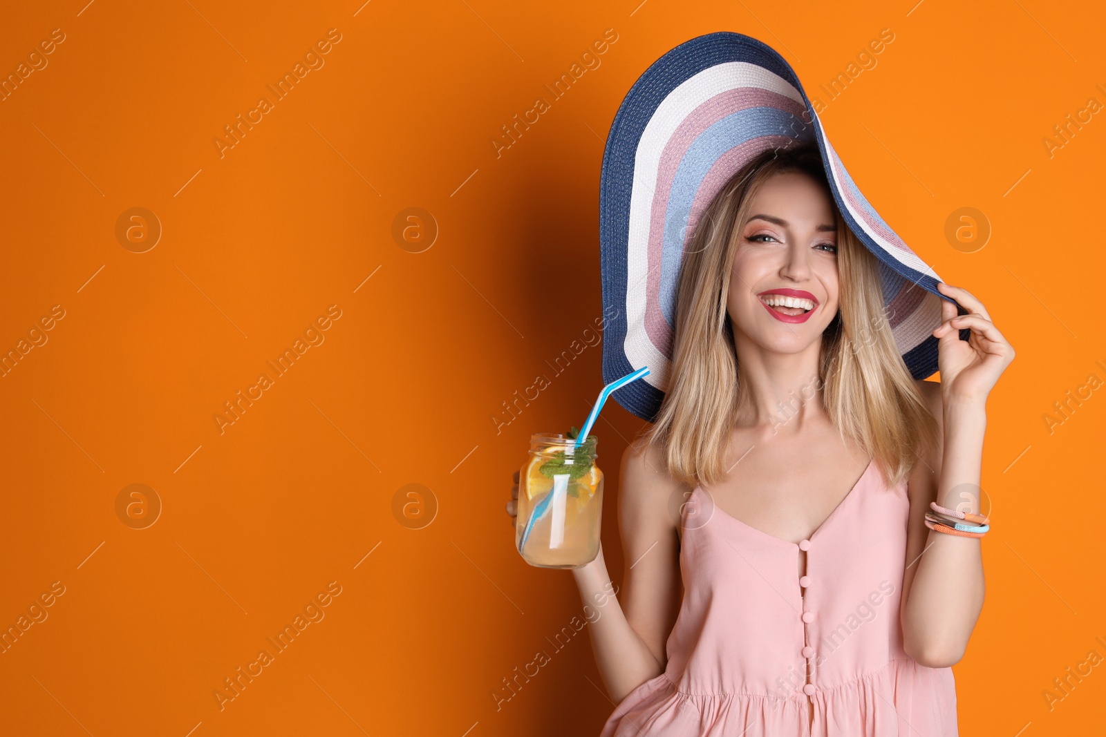 Photo of Young woman with mason jar of tasty lemonade on color background. Natural detox drink