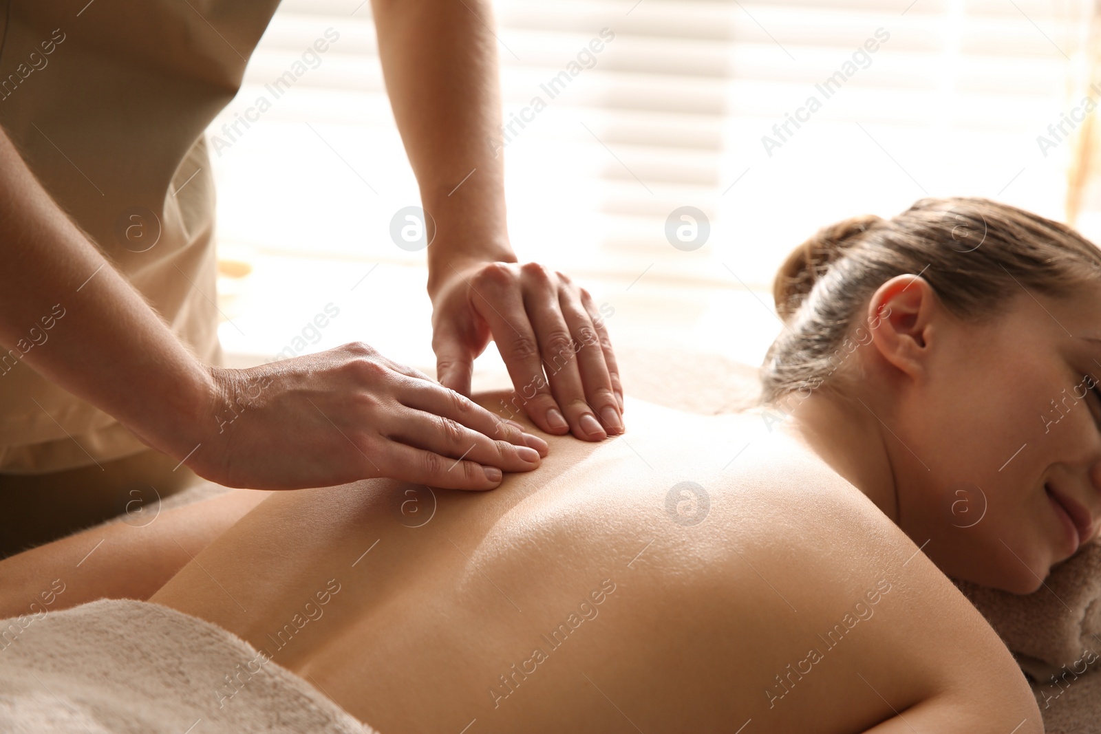 Photo of Young woman receiving back massage in spa salon, closeup