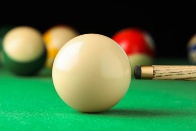 Photo of Classic plain billiard ball and cue on green table, closeup
