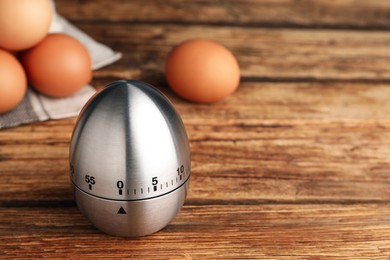 Kitchen timer and eggs on wooden table. Space for text