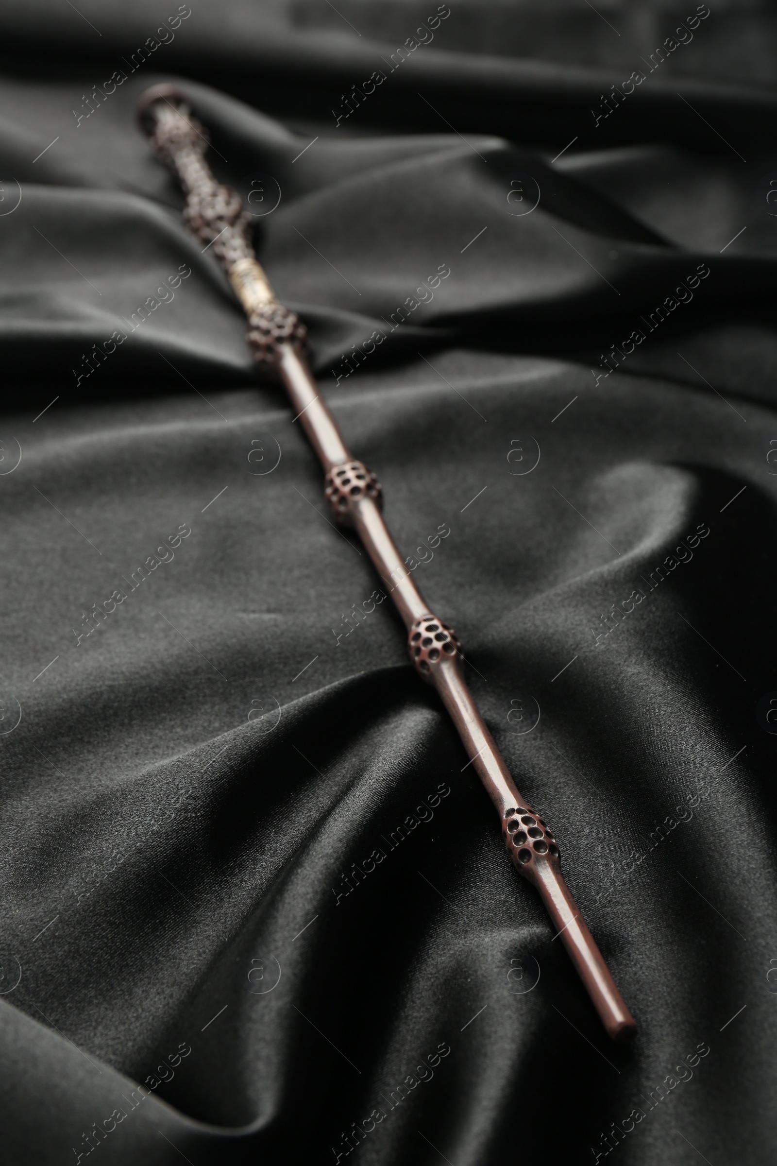 Photo of One magic wand on black fabric, closeup view
