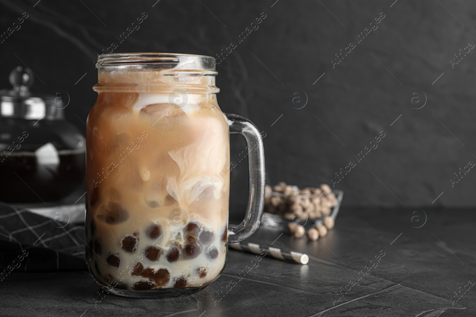 Photo of Tasty brown milk bubble tea on grey table, closeup. Space for text