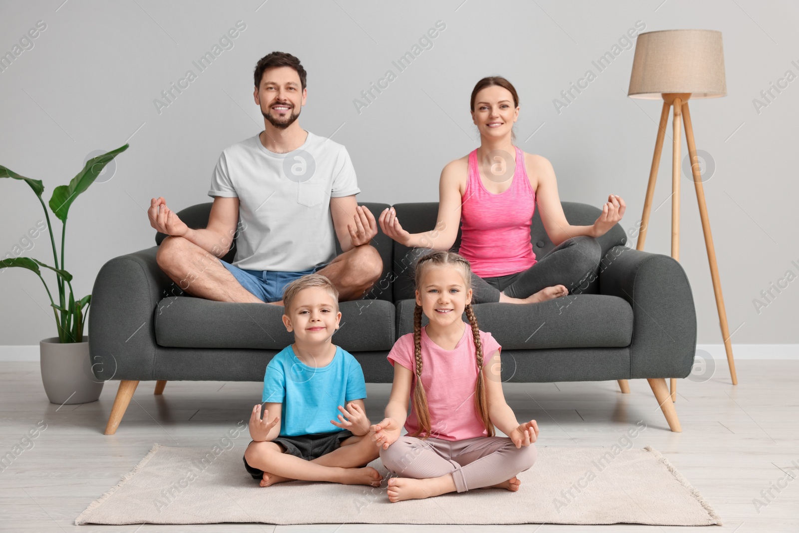 Photo of Happy family meditating together at home. Harmony and zen