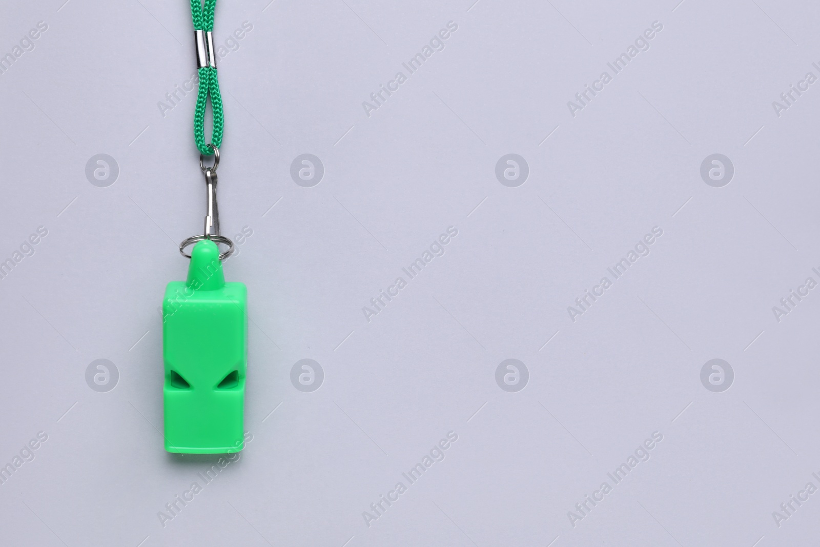 Photo of One green whistle with cord on light grey background, top view. Space for text