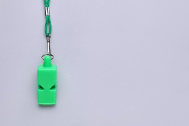 One green whistle with cord on light grey background, top view. Space for text