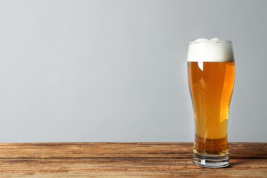 Glass of tasty beer on wooden table. Space for text