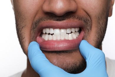 Dentist examining man's gums on white background, closeup