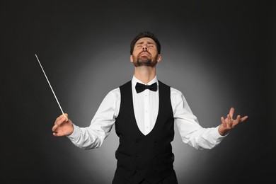 Professional conductor with baton on black background