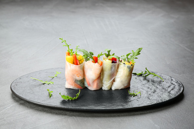 Delicious rolls wrapped in rice paper served on grey table